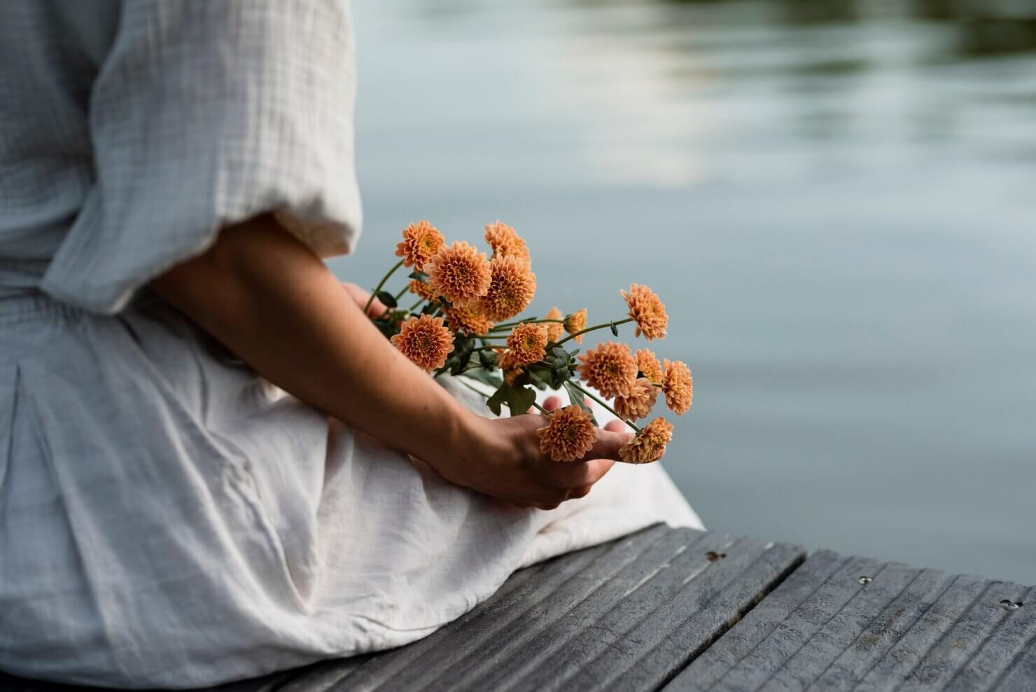 Vrouw met bloemen aan het water